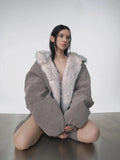 Reversible oversized hooded winter coat for women, gray padded bomber jacket side with white faux fur lining visible, styled with shorts and knee socks